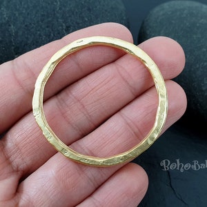 May include: A gold-toned metal ring with a hammered texture. The ring is thick and has a rounded shape.