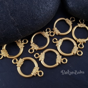 May include: Eight gold-toned metal ring clasps with intricate floral designs. Each clasp has two loops for attaching jewelry.
