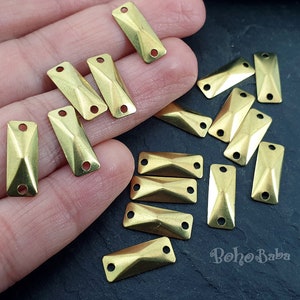 Pode incluir: Uma coleção de 12 enfeites retangulares de metal dourado com um design em forma de diamante. Os enfeites têm dois furos de cada lado para serem presos a joias ou outros artesanatos.