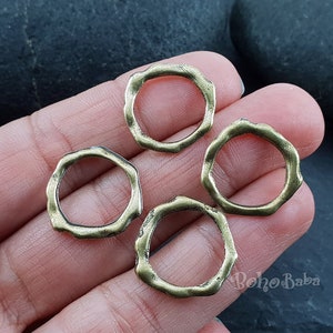 Op de afbeelding: Vier antieke goudkleurige metalen ringen met een onregelmatig, licht bobbelig, getextureerd oppervlak. De ringen hebben een diameter van ongeveer 2,5 cm.