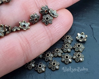 May include: A collection of antique gold-toned metal flower-shaped bead caps. The bead caps have a detailed design and are perfect for adding a touch of elegance to jewelry projects.