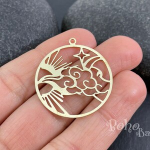 Könnte beinhalten: Goldfarbener Metall-Anhänger mit einem ausgeschnittenen Design einer Wolke mit einem Stern und Sonnenstrahlen. Der Anhänger ist rund und hat oben ein Loch zum Anbringen an einer Halskette oder einem Armband.