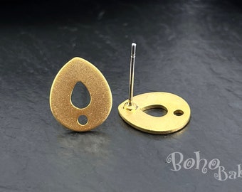 May include: A pair of gold-toned earrings with a teardrop shape and a small hole in the center. The earrings are made of metal and have a textured surface.