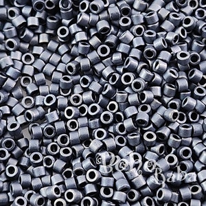 Puede incluir: Vista de cerca de una gran cantidad de pequeñas cuentas redondas de color plateado. Las cuentas tienen un acabado metálico y están dispuestas en un patrón aleatorio.