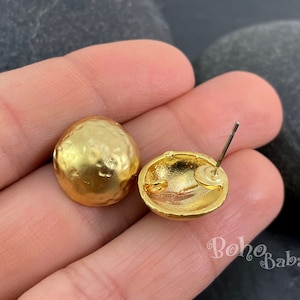 Puede incluir: Un par de pendientes de botón dorados con un diseño redondo texturizado. Los pendientes tienen un poste y un cierre de mariposa.
