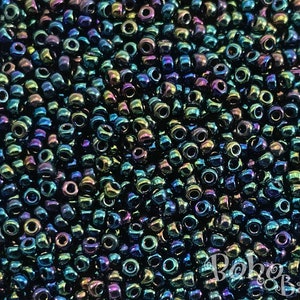 Op de afbeelding: Een close-up van een grote hoeveelheid kleine, ronde, iriserende kralen. De kralen zijn diepblauwgroen met een metallic glans.