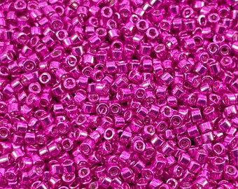 May include: A close-up image of a large quantity of small, shiny, metallic pink beads. The beads are round and have a smooth, polished finish.