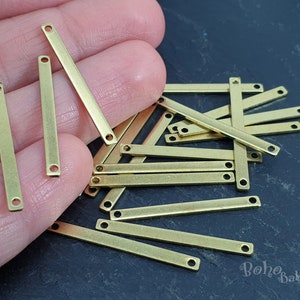 May include: A pile of gold-colored metal bar connectors with two holes on each end. The connectors are approximately 1 inch long.