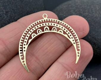 May include: Gold-toned metal crescent moon pendant with intricate geometric designs. The pendant has a loop at the top for attaching to a chain or cord.