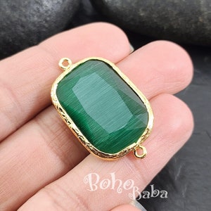 May include: Gold-toned pendant with a green glass cabochon in a rectangular shape. The pendant has two jump rings for attaching to a chain or cord.