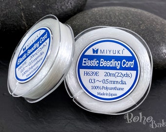 Puede incluir: Dos carretes de cordón elástico transparente para hacer bisutería, cada uno con una etiqueta azul que dice "MIYUKI Elastic Beading Cord H639E 20m(22yds) 0.3~0.5mm dia. 100% Polyurethane Made in Japan"
