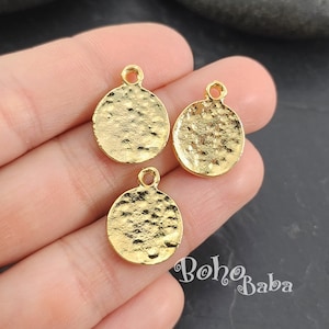 Puede incluir: Tres dijes circulares de metal dorado con textura martillada y un bucle en la parte superior para sujetar a joyas u otras manualidades.