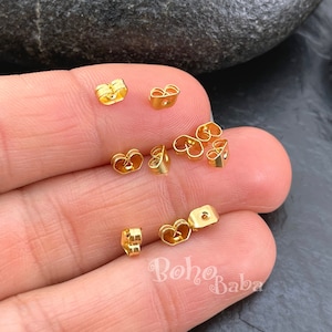 以下が含まれることがあります： イヤリングを固定するための、蝶々型とも呼ばれるゴールドトーンのイヤリングバック。バックは金属製で、イヤリングポストを通すための小さな穴が中央にあります。画像には9つのイヤリングバックがあります。