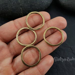 May include: Four gold-colored metal rings of different sizes. The rings are smooth and have a slightly textured surface.
