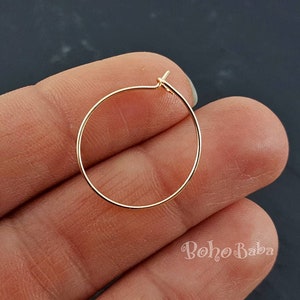 Pode incluir: Um brinco de argola de ouro simples. O brinco é pequeno e delicado, e é perfeito para o uso diário.