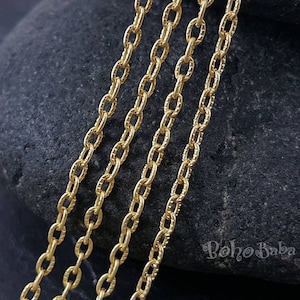 Könnte beinhalten: Vier Stränge goldene Kette mit einer strukturierten Oberfläche. Die Ketten sind versetzt angeordnet, wobei die oberste Kette die kürzeste und die unterste Kette die längste ist.