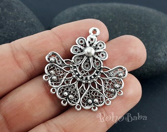 May include: Silver filigree pendant with a floral design. The pendant has a loop at the top for attaching to a chain or cord.
