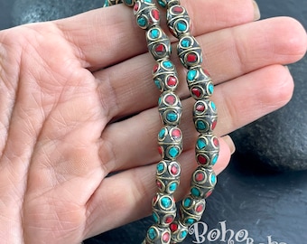 May include: Two strands of oval-shaped beads with a brass finish. The beads are decorated with turquoise and red accents.