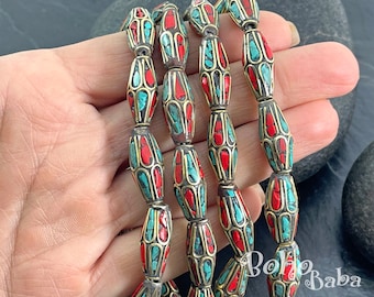 May include: Strands of ornate beads with a mix of red and turquoise stones set in a silver-tone metal with gold accents. The beads have an elongated barrel shape. The image is of a jewelry item.