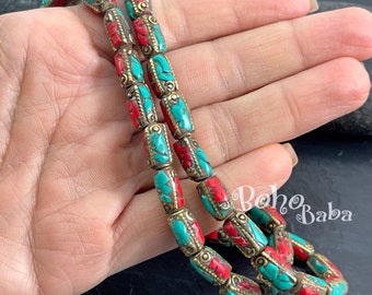 May include: Two strands of turquoise and red bead necklace with gold accents. The beads are cylindrical and have a decorative pattern. The necklace is displayed on a hand.