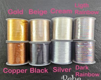 May include: Eight spools of thread in various colors, including gold, beige, cream, light rainbow, copper, black, silver, and dark rainbow. The spools are labeled with their respective colors. The brand name "Boho Baba" is visible in the bottom right corner.