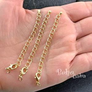 May include: Three gold extender chains with lobster claw clasps and ball end caps. The chains are approximately 2 inches long.