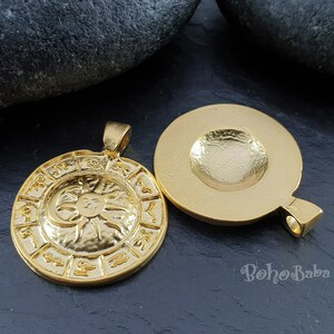 May include: Gold-toned pendant featuring a circular design with zodiac symbols and a sun and moon graphic. The back of the pendant is plain.