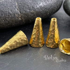 Puede incluir: Cuatro cuentas de metal de color dorado en forma de cono con textura martillada. Las cuentas miden aproximadamente 2,5 cm de largo.