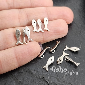 May include: Silver fish charms with a hole for attaching to jewellery or other crafts. The charms are approximately 2.5 cm long and have a simple, elegant design.