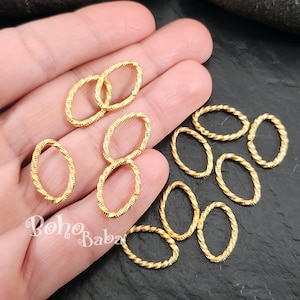 May include: Gold-coloured oval-shaped jewellery findings with textured surfaces. The findings are in various orientations, some overlapping. The image includes the text "Boho Baba" in a script font.