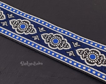 Puede incluir: Borde con estampado azul y plateado con un diseño floral repetitivo. El borde tiene un fondo negro con detalles plateados y azules.