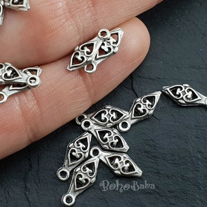 Puede incluir: Encantos de conector de metal plateado con un diseño de filigrana decorativo. Los encantos tienen forma de diamante con un bucle en cada extremo.