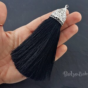Puede incluir: Borla negra con una parte superior de metal plateado. La borla est&aacute; hecha de finos hilos de tela y tiene una parte superior de metal decorativa y adornada.