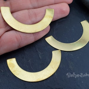 May include: Three gold-colored metal half-circle shapes, or half-rounds, are shown on a dark surface. The half-rounds are approximately 2 inches in diameter.