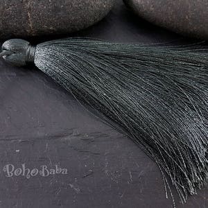 May include: A dark green tassel with a long, flowing fringe. The tassel is made of a soft, silky material and has a simple, elegant design.
