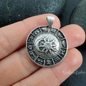 May include: Silver pendant featuring a circular design with the zodiac symbols and a sun and moon graphic.