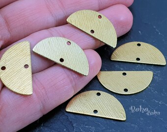 May include: Six gold-toned metal half-circle shapes with two holes each. The shapes have a textured surface and are arranged on a dark surface.