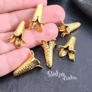 Puede incluir: Seis tapones de cuentas de metal dorado en forma de flor con una superficie texturizada. Los tapones miden aproximadamente 2,5 cm de largo.