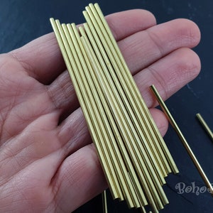 May include: A close-up of a hand holding a bundle of 16 gold-colored metal rods. The rods are approximately 6 inches long and have a smooth, polished finish.