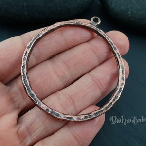 May include: A large, hammered copper circle pendant with a loop at the top. The pendant is about 2 inches in diameter and has a rustic, antique look.