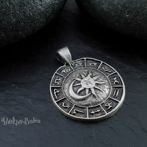 May include: Silver pendant featuring a sun and moon design with zodiac symbols around the edge.