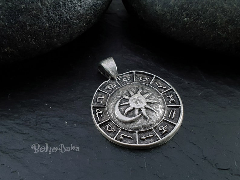 May include: Silver pendant featuring a sun and moon design with zodiac symbols around the edge.