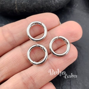 Puede incluir: Tres anillos de metal plateado con cierre de resorte. Los anillos tienen un diámetro de aproximadamente 2,5 cm.