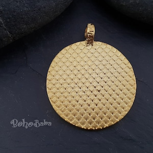May include: Gold-toned round pendant with a textured diamond pattern. The pendant has a loop at the top for attaching to a chain.