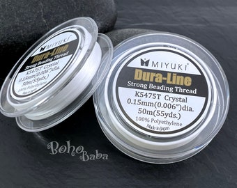 Può includere: Due bobine di filo per perline Miyuki Dura-Line bianco resistente. Ogni bobina è etichettata con il nome del marchio, il nome del prodotto e dettagli come la dimensione del filo (0,15 mm o 0,006 pollici) e la lunghezza (50 metri o 55 iarde).