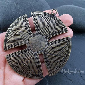 May include: A large, round, brass pendant with a geometric design. The pendant has a loop at the top for hanging. The pendant is approximately 12.5 cm in diameter.