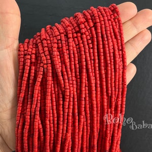 May include: A strand of red wooden beads, approximately 6mm in diameter, with a square shape. The beads are strung on a thin cord and are arranged in a neat, uniform pattern.