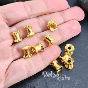 May include: Gold-toned metal beads with a decorative, fluted design. The beads are approximately 1 inch in diameter and have a hole in the center for stringing.