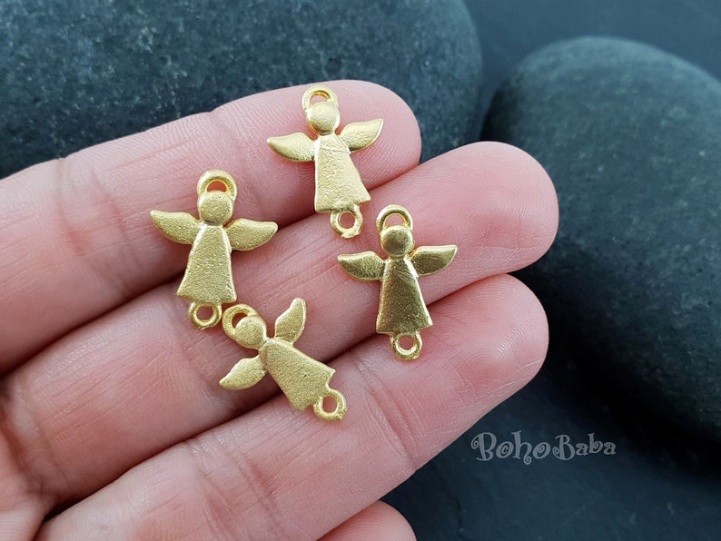 Pu&ograve; includere: Quattro ciondoli a forma di angelo dorati con un anello in cima per attaccarli a gioielli o altri oggetti artigianali.