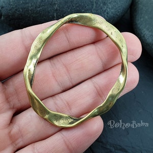 May include: A thick, gold-toned, metal ring with a wavy, irregular shape.
